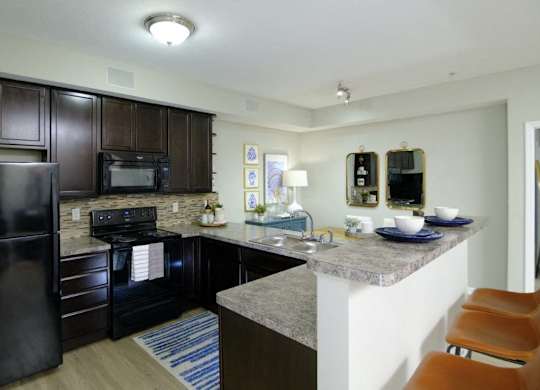 A kitchen with a black refrigerator and a black microwave.