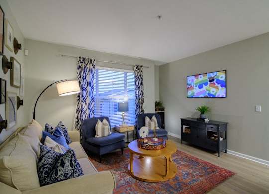 A living room with a couch, chair, and a television mounted on the wall.