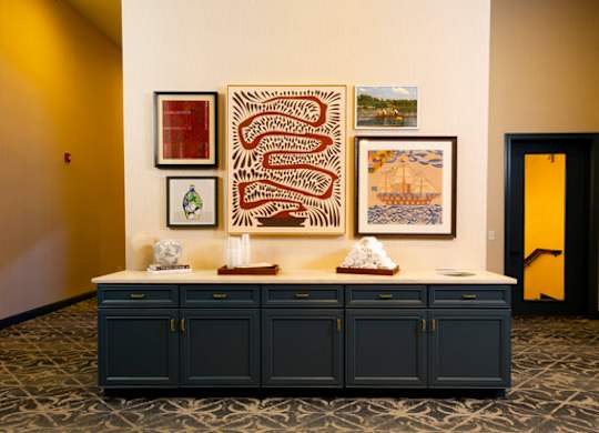 A room with a patterned carpet and a cabinet with pictures on the wall.