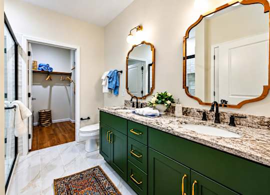 A bathroom with green cabinets and a marble counter.