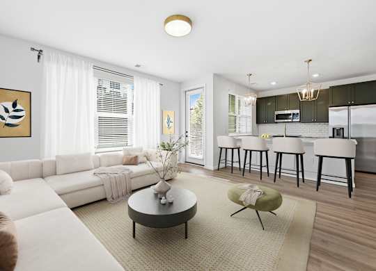 A modern living room with a white sofa, a coffee table, and a kitchen area in the background.