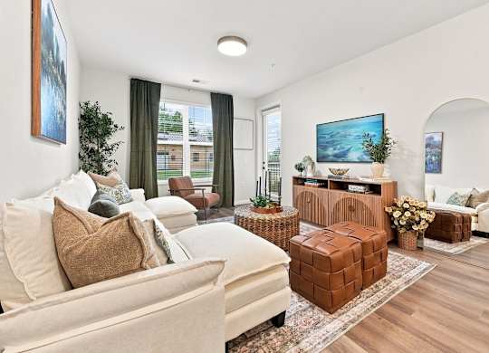 A living room with a white couch and a brown ottoman.