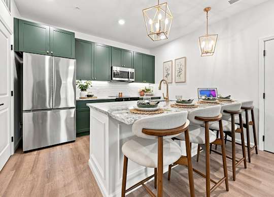 A kitchen with a white island and green cabinets.