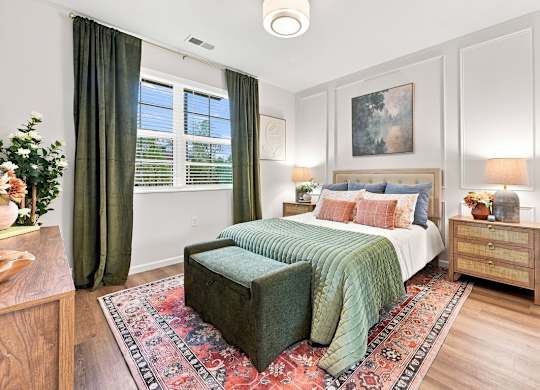 A bedroom with a bed, nightstand, and a rug.