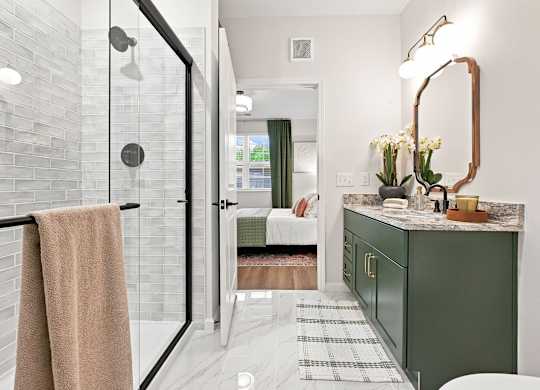 A bathroom with a green cabinet and a glass shower door.