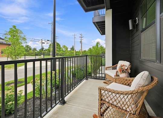 A balcony with a chair and a table with a vase of flowers on it.