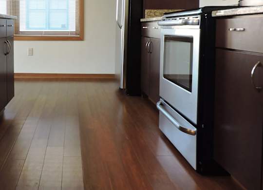 A kitchen with dark wood floors and stainless steel appliances at Cornerstone & Ravenna* Apartments, Shorewood