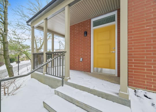 a yellow door on a brick building in the snow
