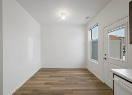 an empty kitchen with white walls and wood flooring and a door