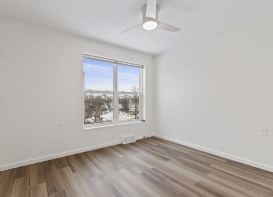 an empty living room with hardwood floors and a large window