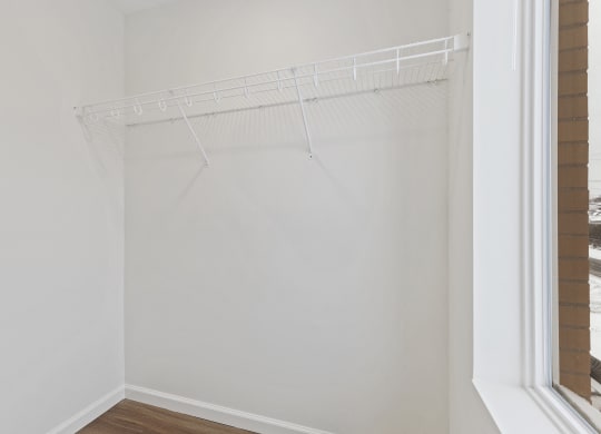 an empty closet with a white wall and a window