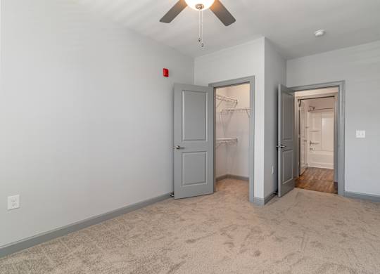 a bedroom with a ceiling fan and a closet with two doors at The Parker Myrtle Beach, Myrtle Beach