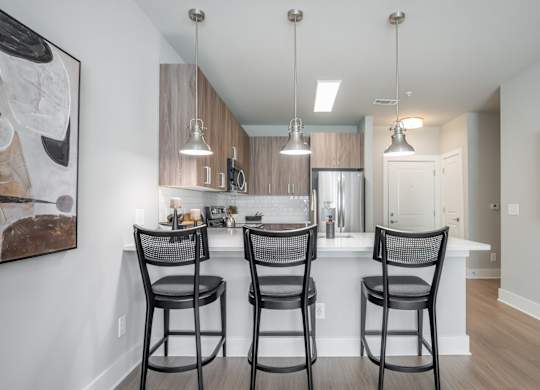 A kitchen with a bar area and chairs.