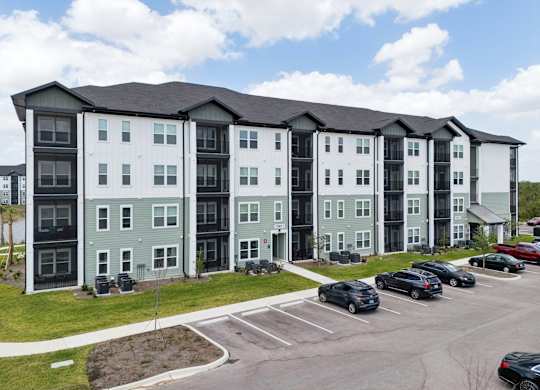 A large apartment complex with a parking lot in front at The Hendry Apartments, Fort Myers, FL