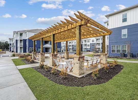 A wooden pavilion is in the middle of a grassy area with a building in the background.at The Parker Leland, Leland North Carolina