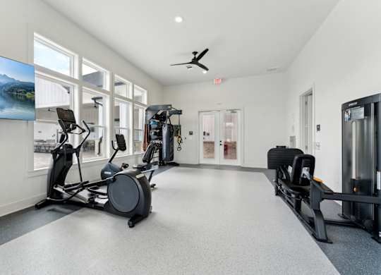 A spacious gym with a variety of equipment including treadmills, stationary bikes, and weight machines at The Hendry Apartments, Fort Myers, Florida