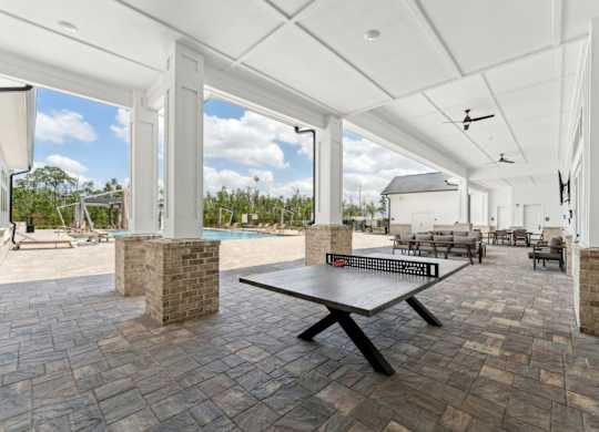 A patio with a table and chairs is covered by a white roof at The Hendry Apartments, Fort Myers, FL