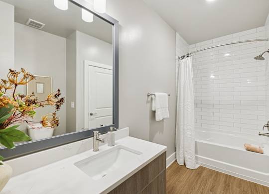 A white sink in a bathroom with a white tub and a white shower curtain at The Beacon at 331 Apartments, Santa Rosa Beach, FL