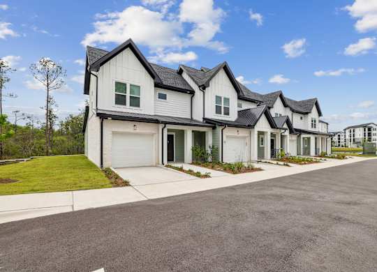 A row of houses with white and black exteriors are lined up on a street at The Beacon at 331 Apartments, Santa Rosa Beach, FL