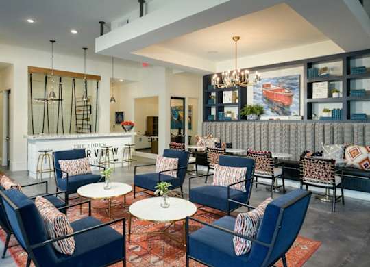 a lounge area with blue chairs and tables and a bar