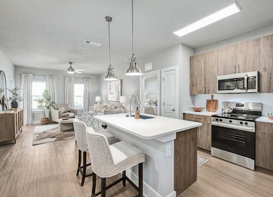 A modern kitchen with a white island and wooden cabinets at The Ashton at East Park Apartments, Georgia