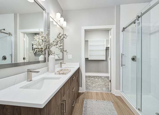 A bathroom with a white sink and a glass shower at The Ashton at East Park Apartments, Kennesaw, Georgia