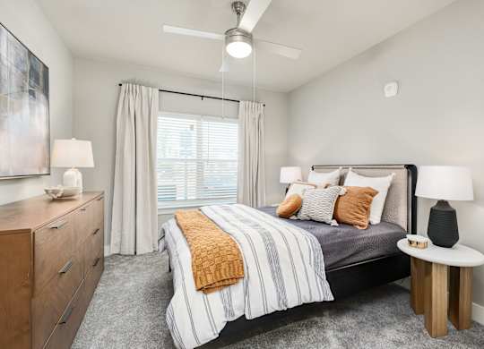 A bedroom with a bed, nightstand, and a painting on the wall at The Ashton at East Park Apartments, Kennesaw, GA