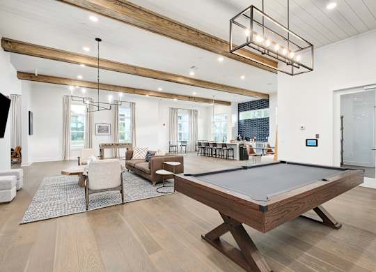 A billiard table is in the middle of a room with a white couch and a TV.
