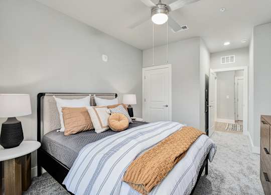 A bedroom with a bed, nightstand, and ceiling fan at The Ashton at East Park Apartments, Kennesaw