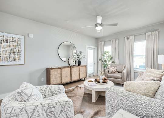 A living room with a white couch, a wooden cabinet, and a painting on the wall at The Ashton at East Park Apartments, Kennesaw, 30144