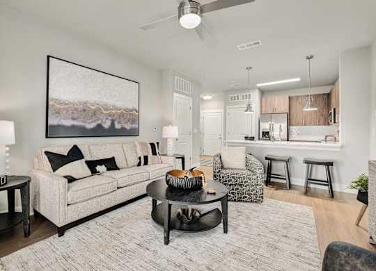 A living room with a large painting on the wall and a white couch at The Ashton at East Park Apartments, Georgia