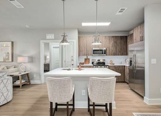 A modern kitchen with a white island and two chairs at The Ashton at East Park Apartments, Kennesaw, GA
