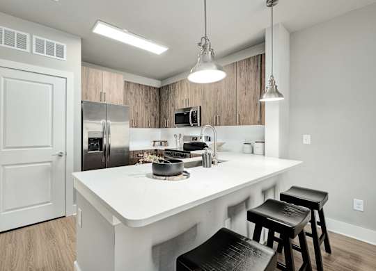 A kitchen with a white countertop and black stools at The Ashton at East Park Apartments, Kennesaw, GA, 30144