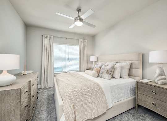 A bedroom with a large bed, two nightstands, and a ceiling fan at The Ashton at East Park Apartments, Georgia, 30144
