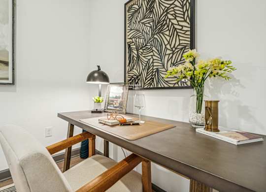a dining table with a chair and a lamp and a vase of flowers at The Leo Myrtle Beach, Myrtle Beach, 29579