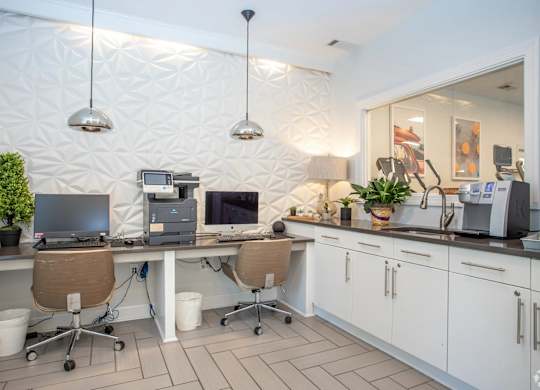 A white kitchen with a desk and chairs.