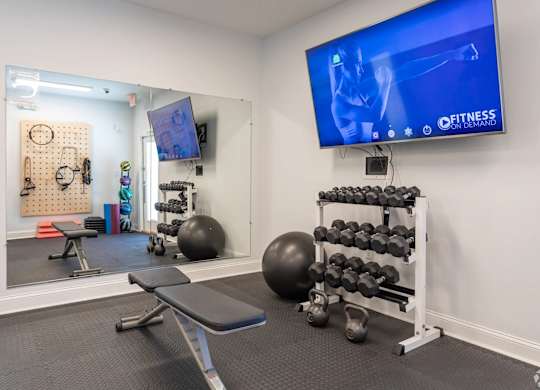A gym room with a television screen showing a fitness program.