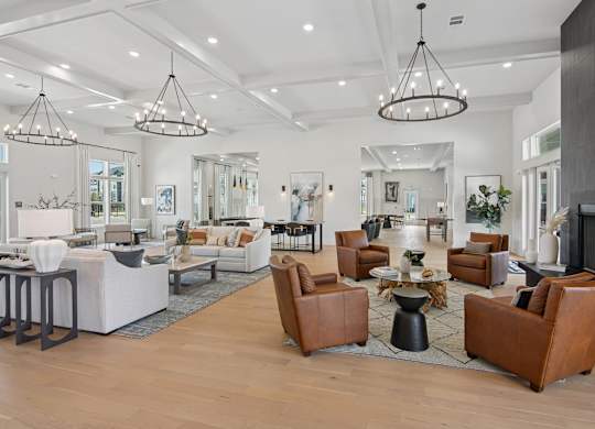A spacious living room with brown leather chairs and a white sofa at The Hendry Apartments, Fort Myers, FL, 33905