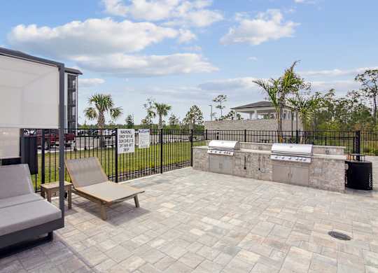 A patio with a grey sofa and a wooden bench at The Hendry Apartments, Fort Myers