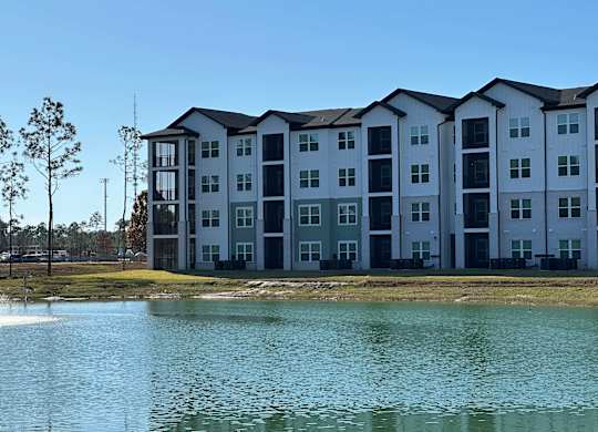 A large white building with a lake in front of it at The Beacon at 331 Apartments, Santa Rosa Beach
