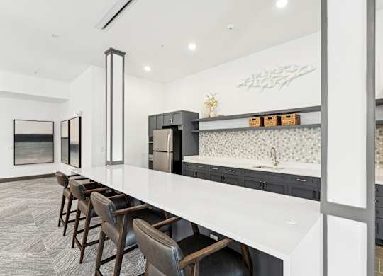 Kitchen with a long counter top and a long island with chairs at The Leo Myrtle Beach, Myrtle Beach, SC