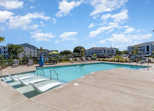 our resort style swimming pool is next to a row of apartment buildings