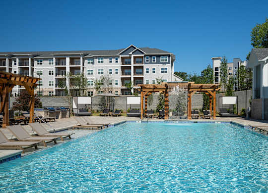 A large swimming pool with lounge chairs and a wooden pergola at The Ashton at East Park Apartments, Kennesaw, 30144