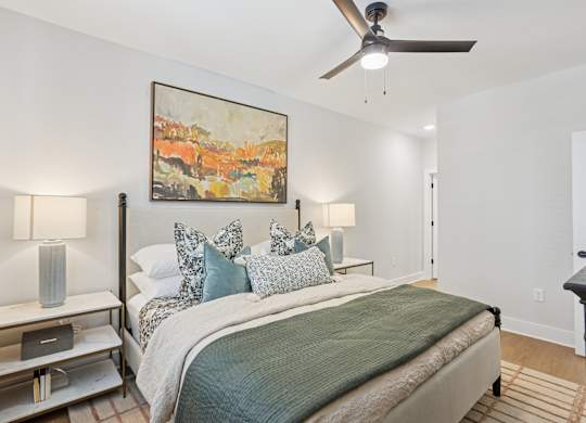 A bedroom with a bed, nightstand, and a painting on the wall at Union Eleven Apartments, Atlanta