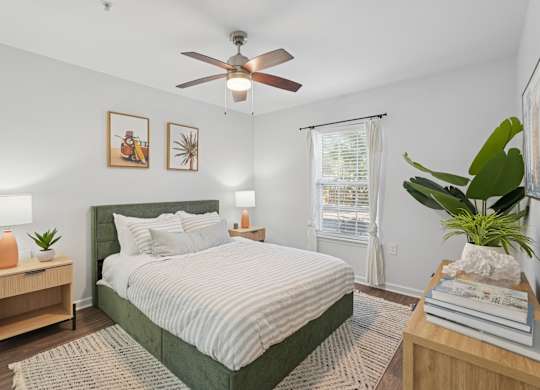 A bedroom with a bed, nightstand, and a ceiling fan.