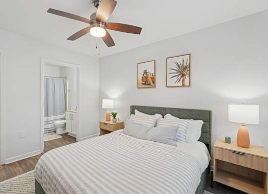 A bedroom with a bed, nightstand, and two wall art pieces.