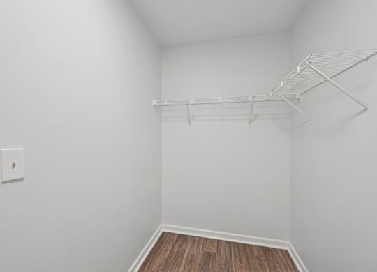 A white wall with a light switch and a white shelf.