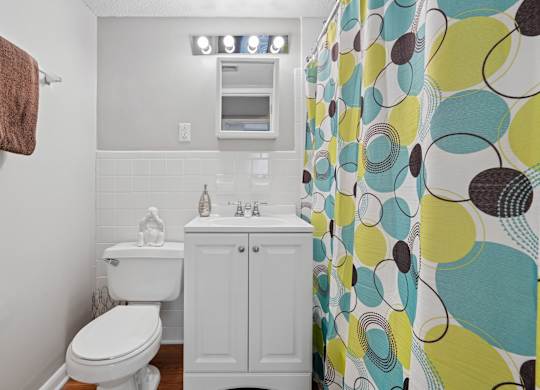 A bathroom with a toilet, sink, and shower curtain.