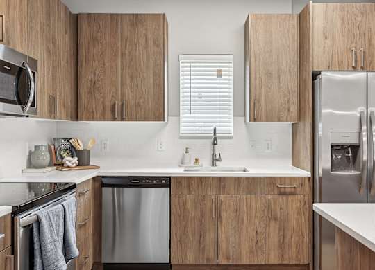 A modern kitchen with wooden cabinets and stainless steel appliances.at The Exchange at Crestview Apartments, Crestview, FL