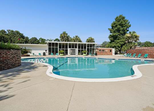 A large outdoor swimming pool with a white building in the background.